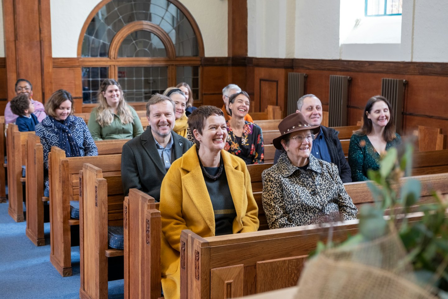 Lachende mensen op kerkbanken kijken naar een evenement.